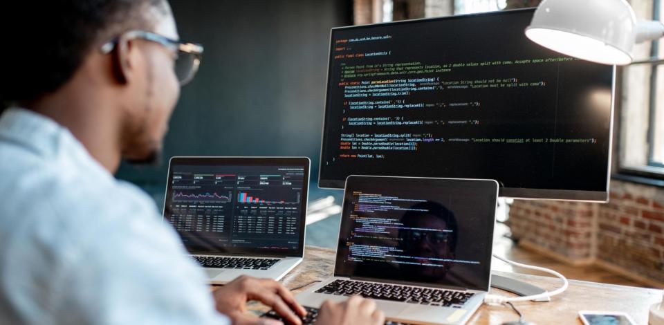 Male programmer writing program code sitting at his workplace