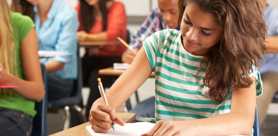 Young female student writing in classroom